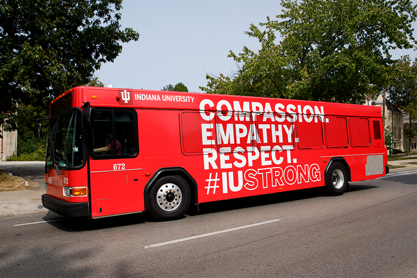 A red bus wrap displays the campaign lockup.